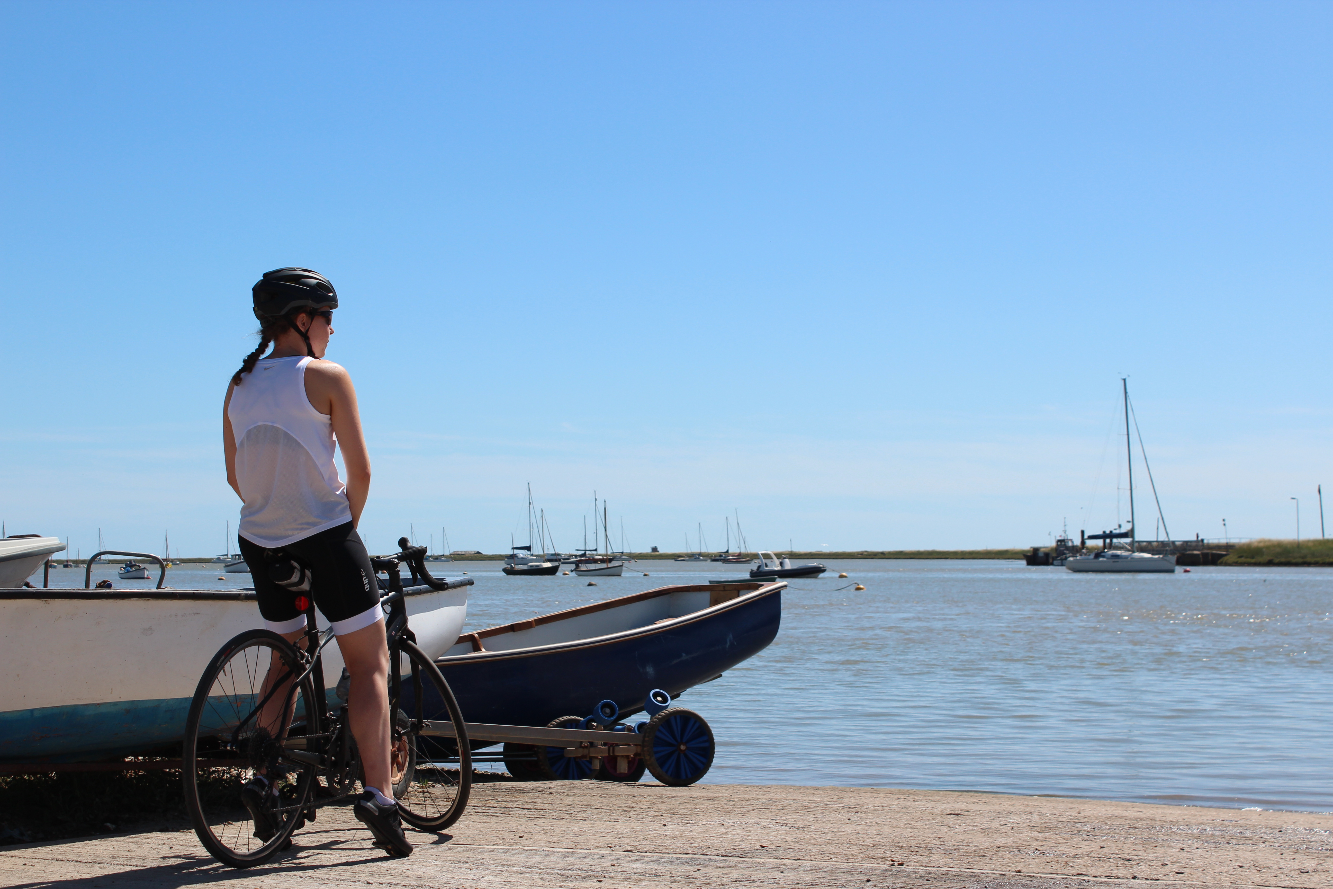 Cyclist pausing at Orford quay, looking out over the Deben estuary