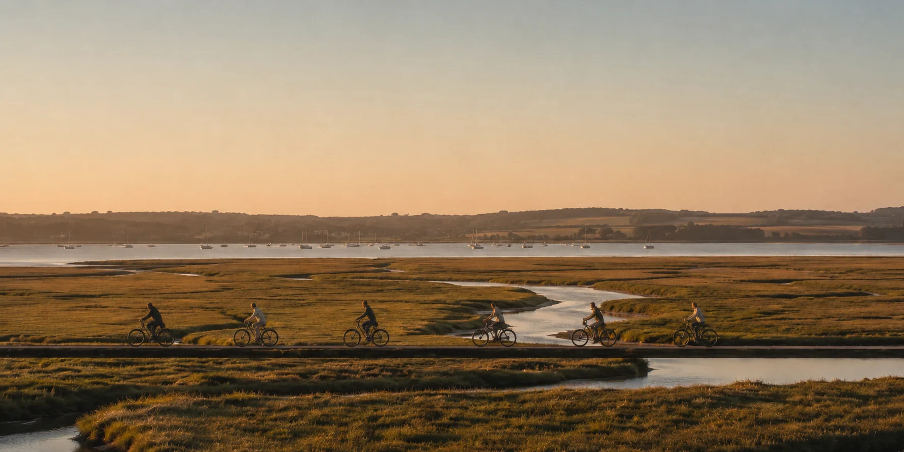 Cyclists crossing a Suffolk estuary bridge in late afternoon light